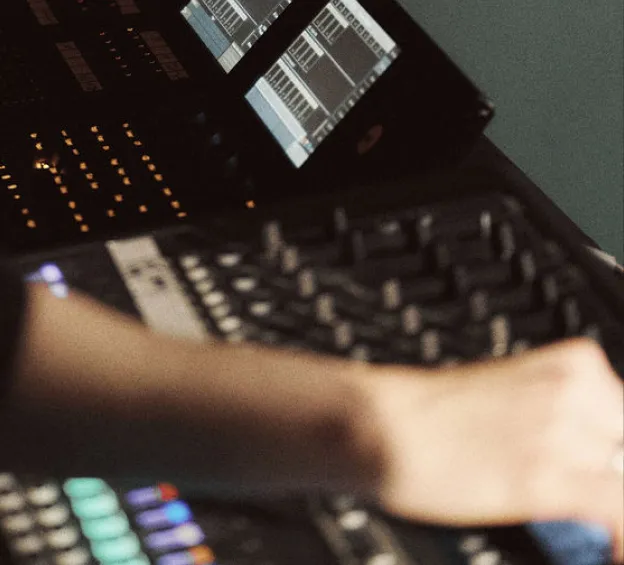 Close-up of a hand adjusting an audio mixing console.