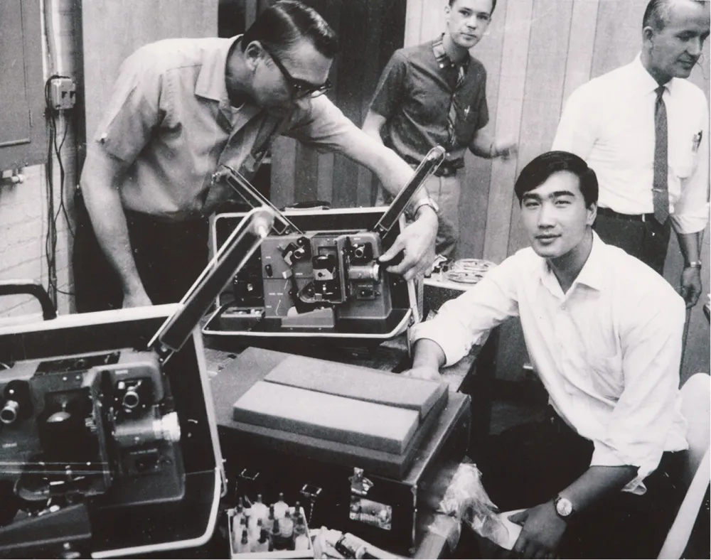 Black-and-white archival photograph of technicians working with equipment cases.