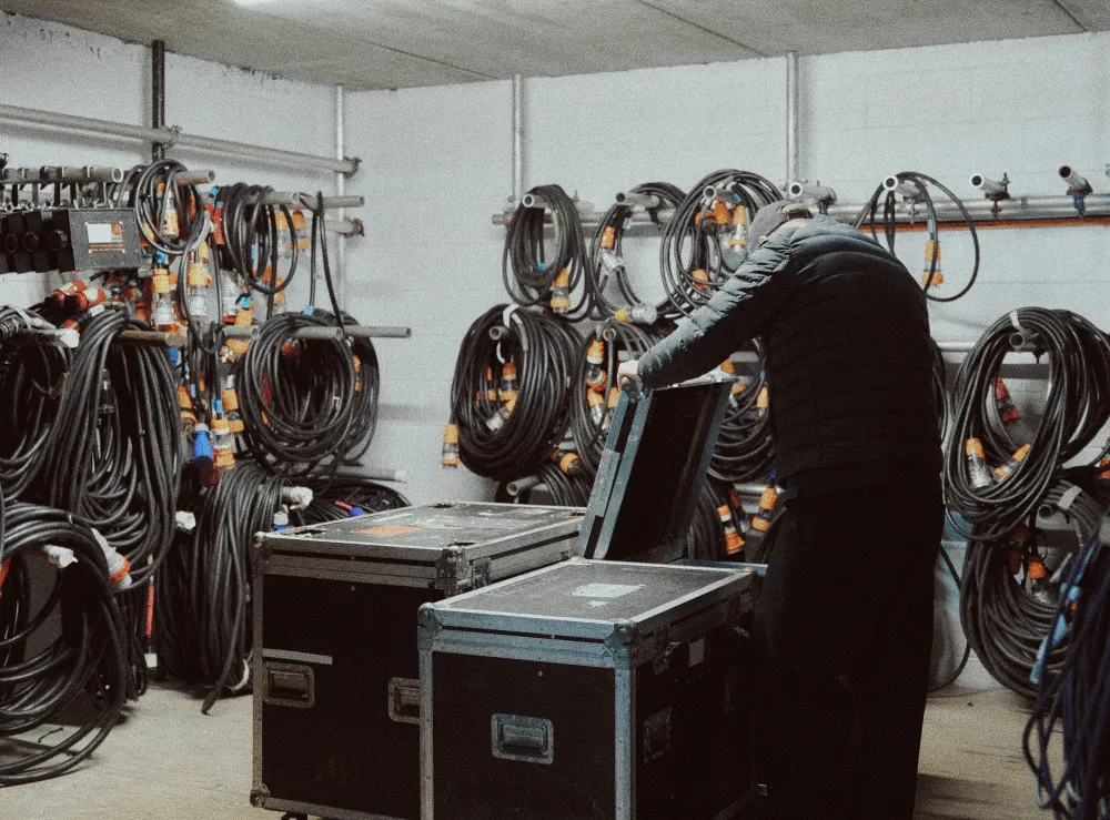 Team member preparing equipment cases beside racks of coiled cables.