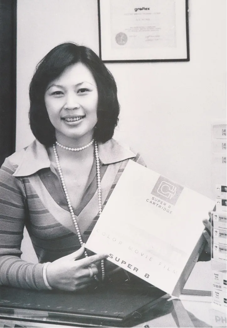 Black-and-white archival portrait of a woman holding an audiovisual equipment case.