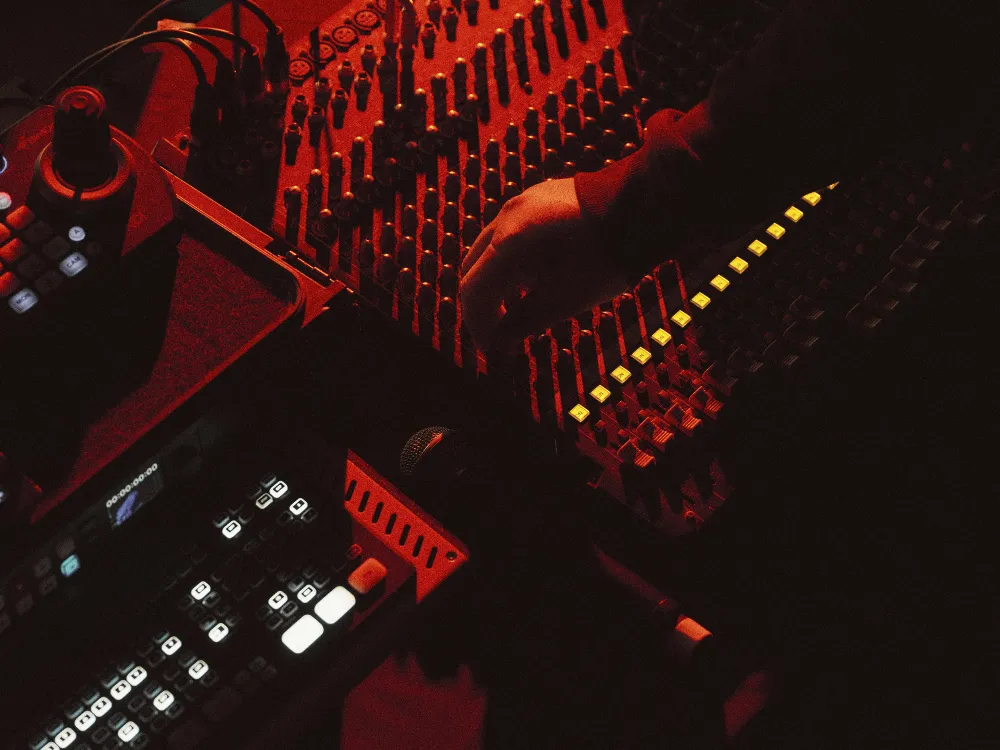 Audio mixing console and equipment rack lit in red.
