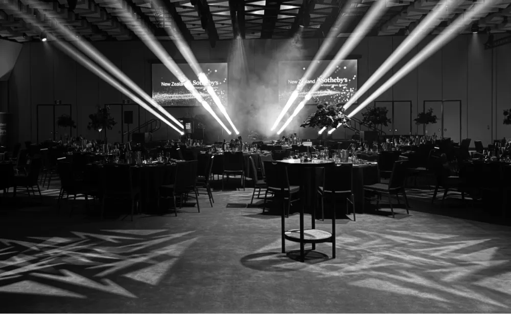 Te Pae Christchurch event space with tables and intersecting stage-light beams.