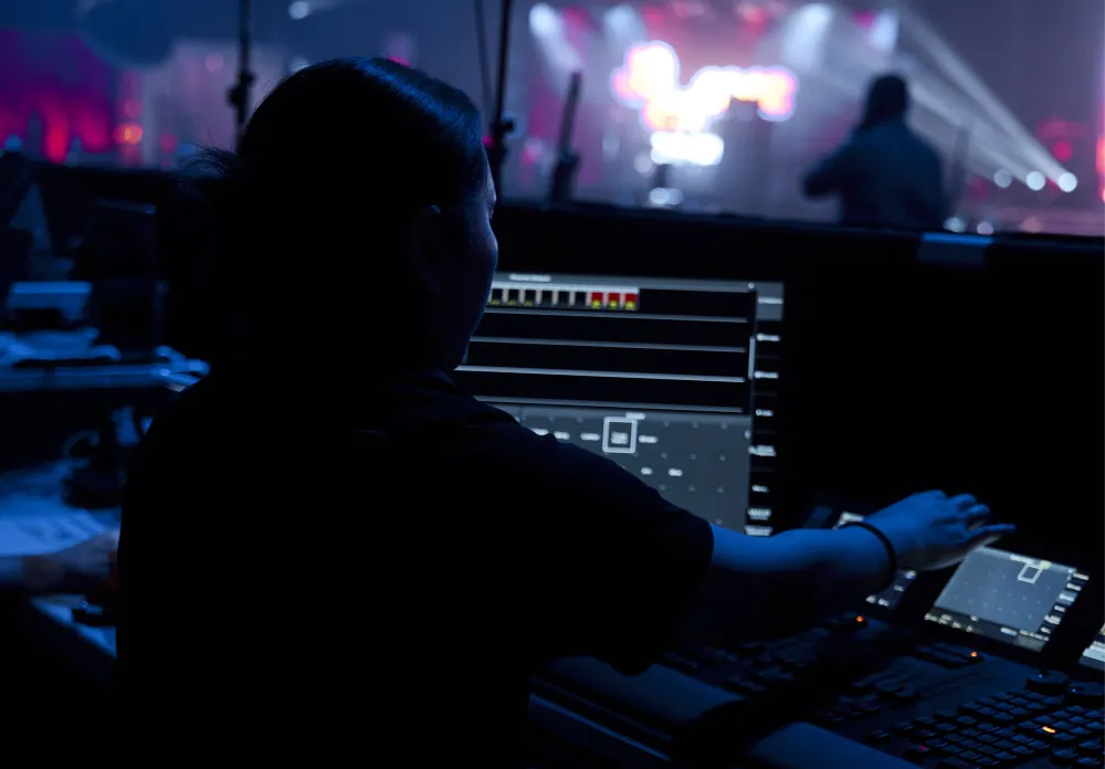 Production operator using a laptop and control desk during a live event.
