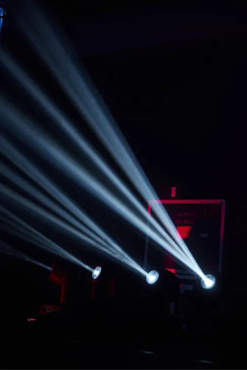 Blue-white stage lighting beams crossing a dark space.