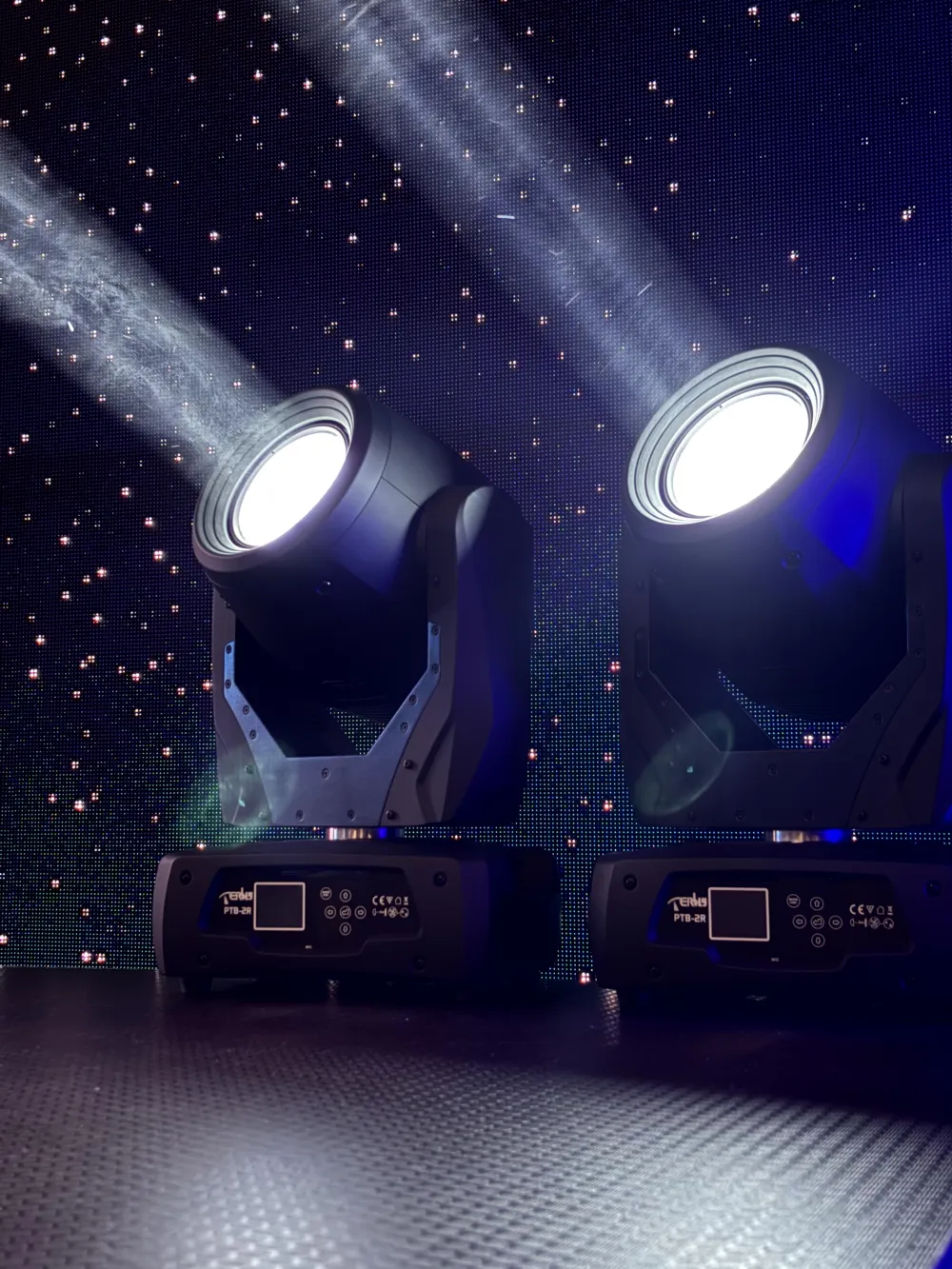 Two stage lights projecting white beams above equipment cases.