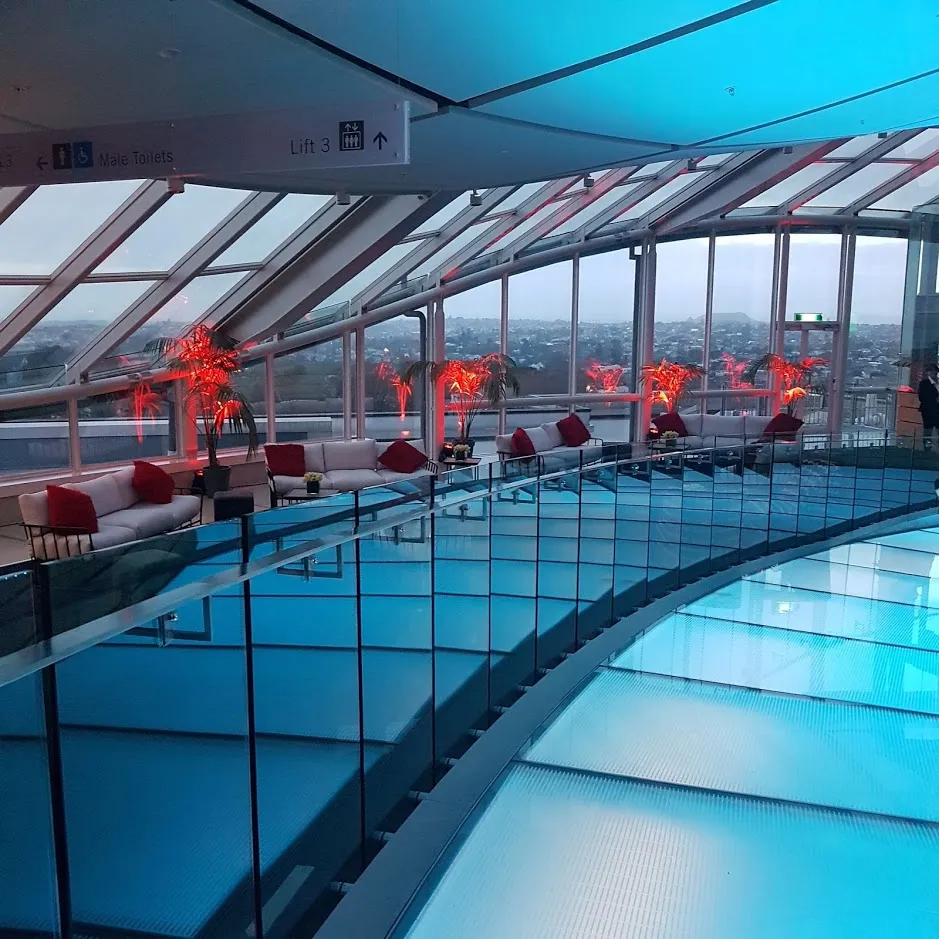 Blue-lit glass walkway overlooking a reception area.
