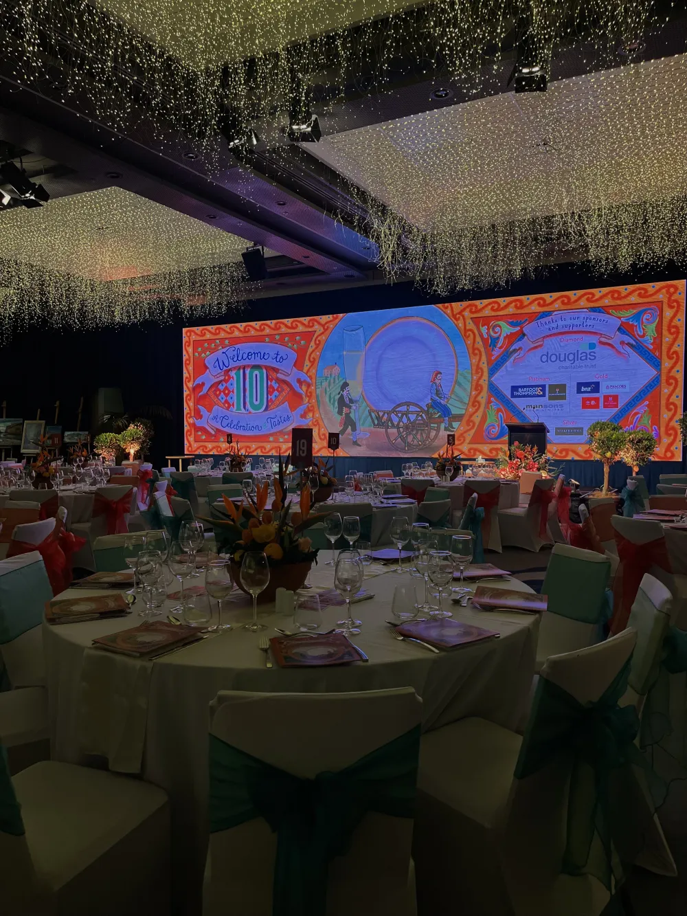 Banquet room with colourful presentation screens behind the stage.