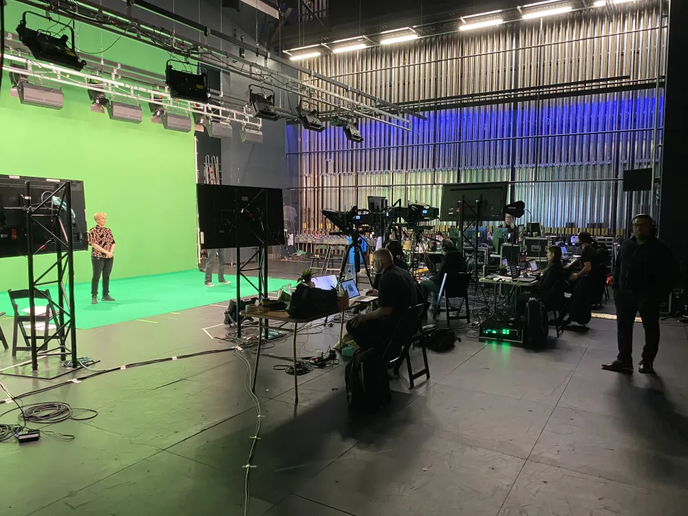 Studio production with a green screen, cameras and crew.