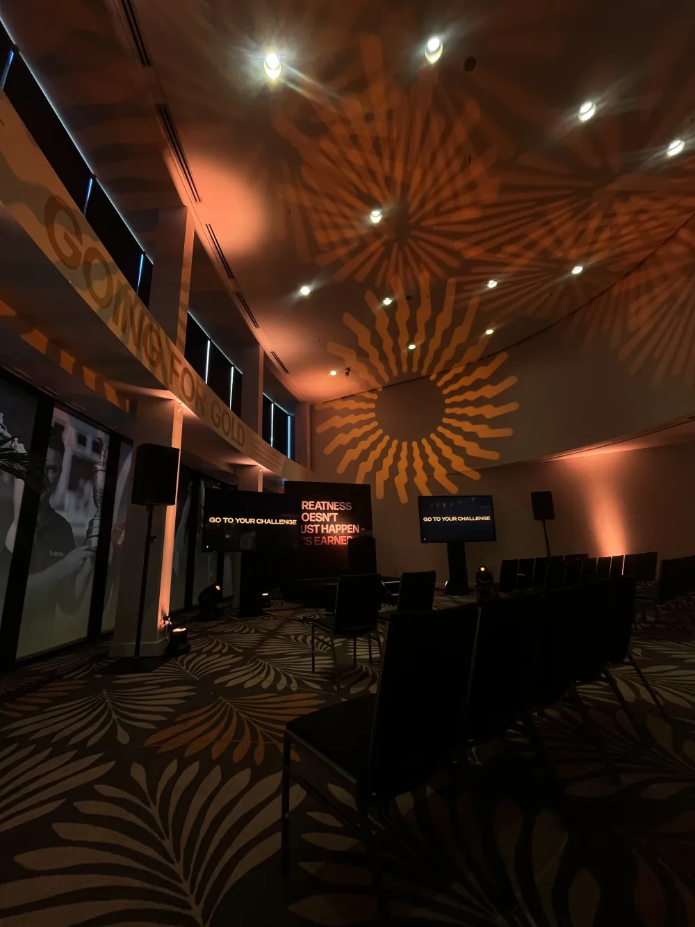 Event room with warm uplighting and patterned light projected onto a wall.
