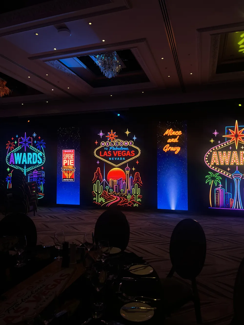 Colourful awards graphics across a row of illuminated stage panels.