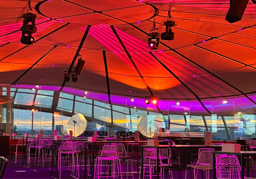 Auckland Museum dome illuminated in red and purple above an event setup.