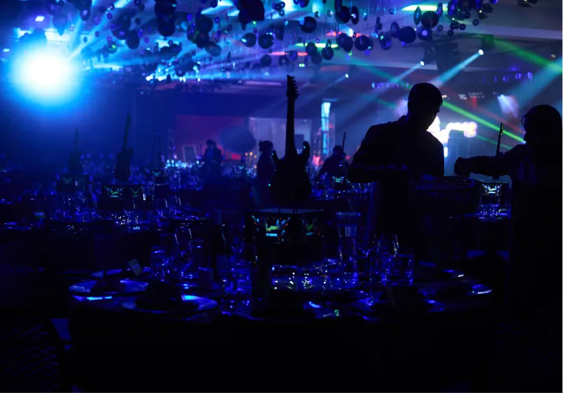 Event production operator silhouetted against blue stage lighting in a banquet hall.